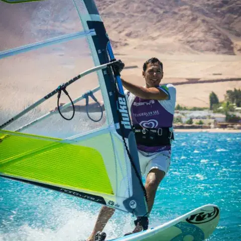 Un windsurfeur en glisse devant les montagnes