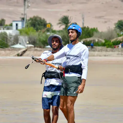 Un moniteur guide un élève sur la plage