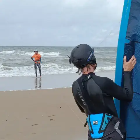 Élève casqué face à la mer, moniteur au loin