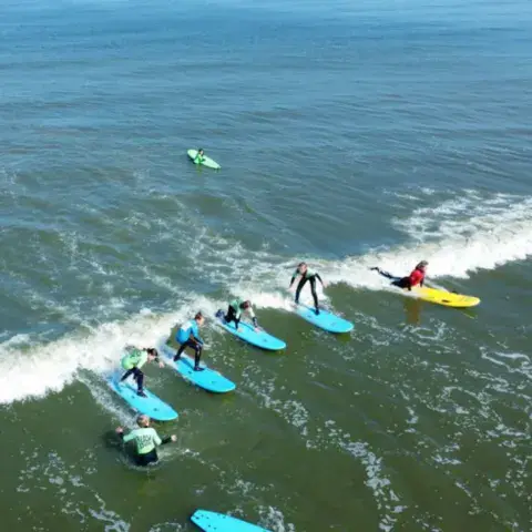 Cours de surf en groupe vu du ciel