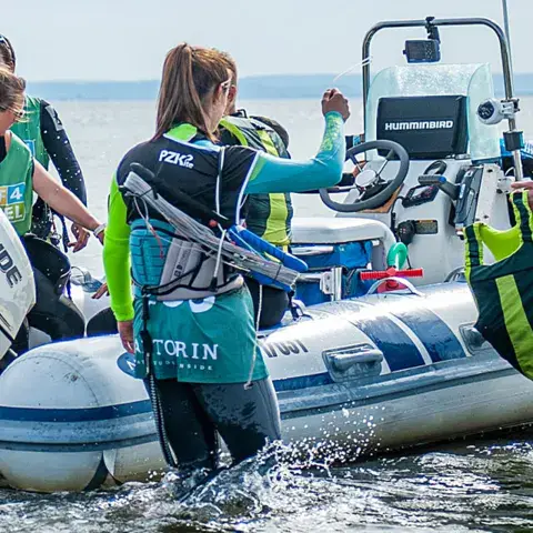 Un groupe d'élèves équipés autour du bateau de sécurité