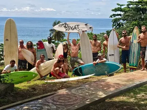 Groupe de surfeurs avec leurs planches devant le camp