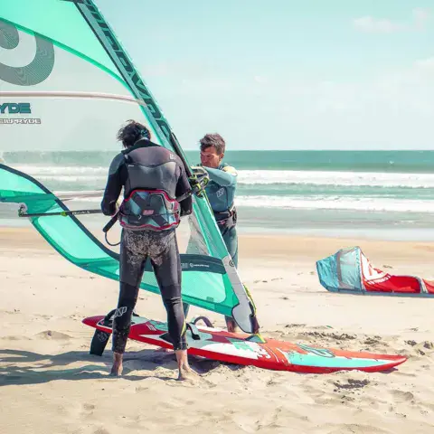Windsurfeurs préparant leur matériel sur la plage