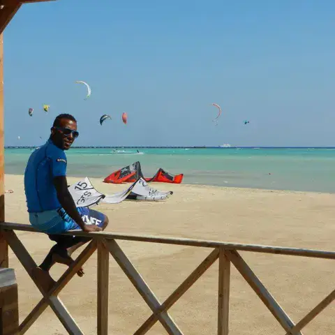 Un moniteur au bord de la plage, kites en l'air derrière lui