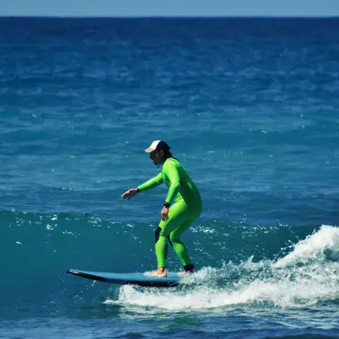 Surfeur en combinaison verte sur une vague