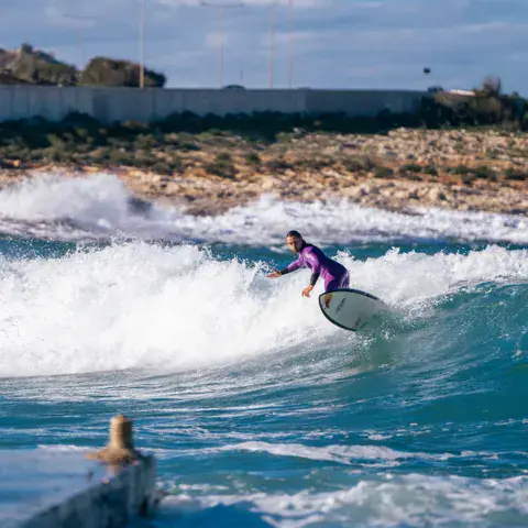 Surfeuse sur une vague près d'une côte rocheuse