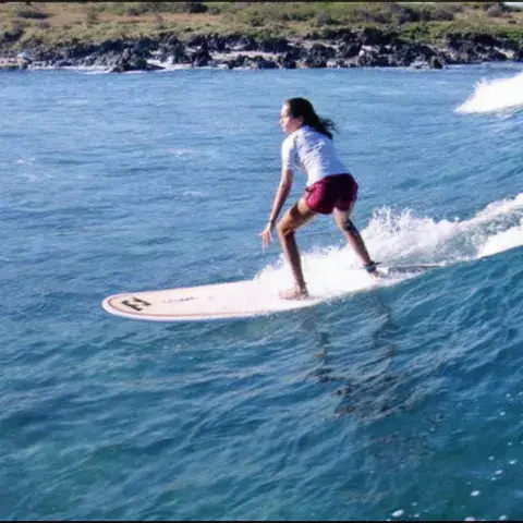 Surfeuse debout sur sa planche dans une vague
