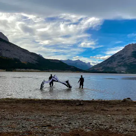 Préparation d'une aile de kite au bord d'un lac de montagne