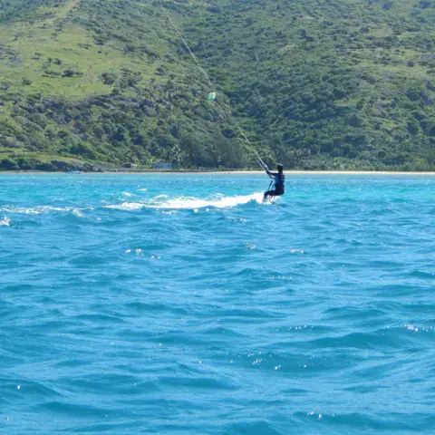 Un kitesurfeur sur le lagon, devant la côte