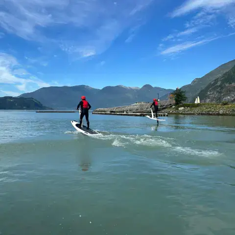 Deux pratiquants de foil sur la baie, montagnes en arrière-plan