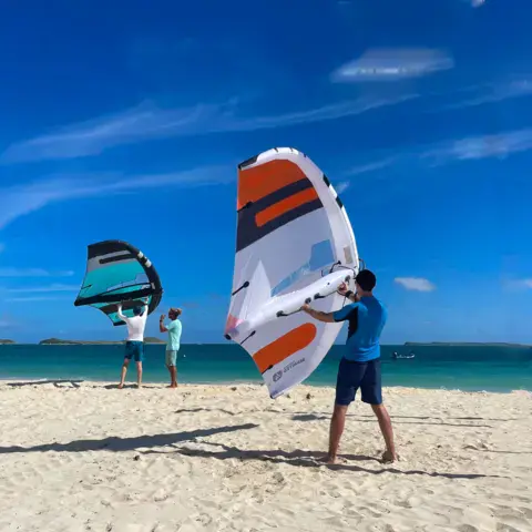Préparation d'ailes de wingfoil sur la plage
