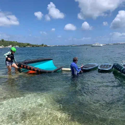 Un élève et un moniteur récupèrent un kite dans l'eau peu profonde