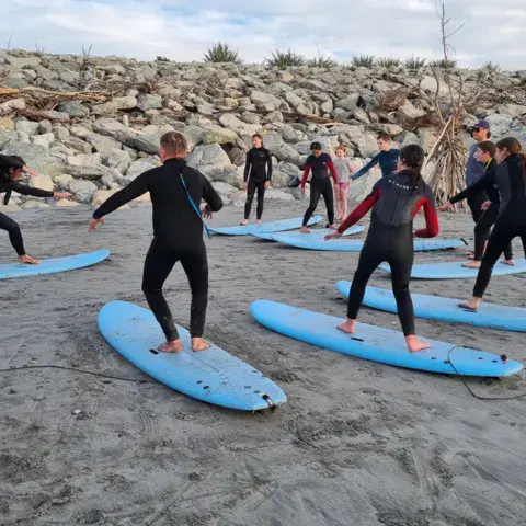 Groupe de surfeurs en combinaison sur une plage de galets