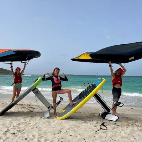 Trois pratiquants avec leurs ailes de wingfoil sur la plage