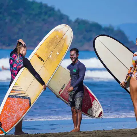 Trois surfeurs avec leurs planches au bord de l'eau