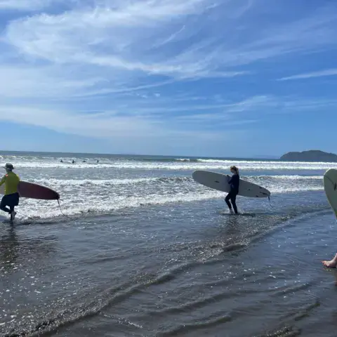 Surfeurs entrant dans l'eau avec leurs planches
