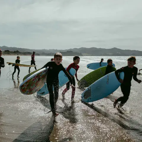 Un groupe porte ses planches vers l'eau