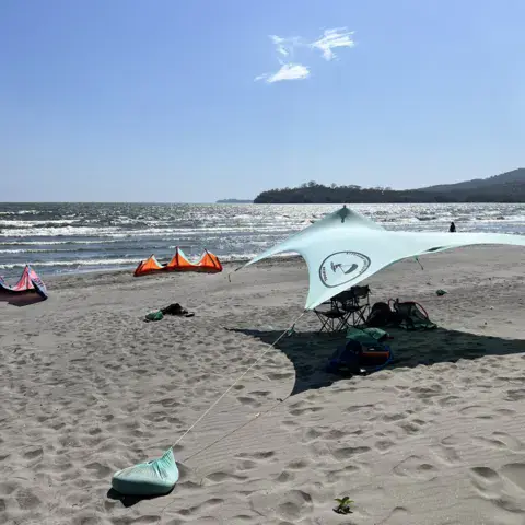 Kites et abri sur la plage, le lac et le volcan en arrière-plan