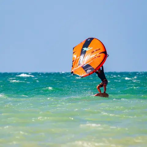 Session de wing foil sur l'eau turquoise du lac