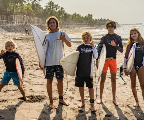 Groupe d'élèves avec leurs planches sur la plage
