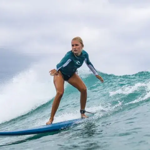 Élève debout sur sa planche pendant un cours de surf