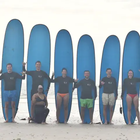 Groupe de surfeurs devant leurs planches bleues alignées