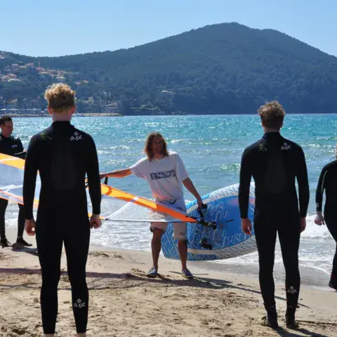 Groupe d'élèves en combinaison sur la plage avec le matériel