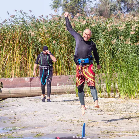 Kitesurfeurs équipés au bord de l'eau, au milieu des roseaux