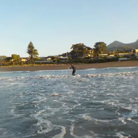 Plage de sable avec un surfeur dans les vagues en fin de journée