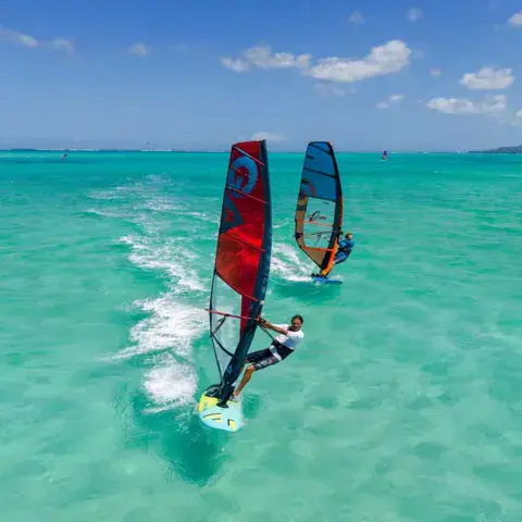 Deux véliplanchistes sur une eau turquoise