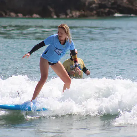 Élève debout sur sa planche dans les vagues