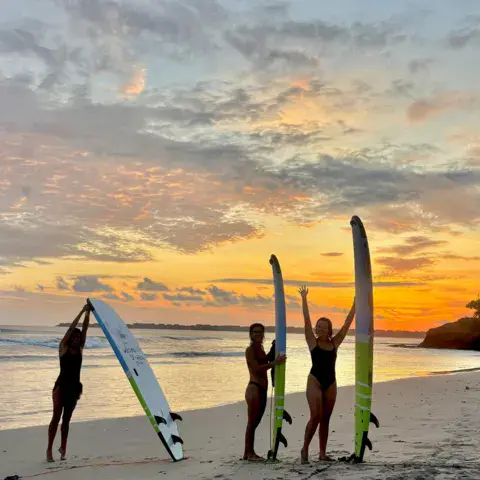 Groupe sur la plage au coucher du soleil, planches dressées