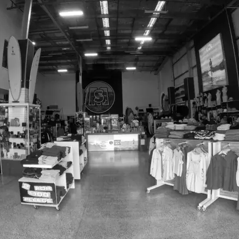Intérieur du magasin en noir et blanc, rayons de vêtements et planches au fond