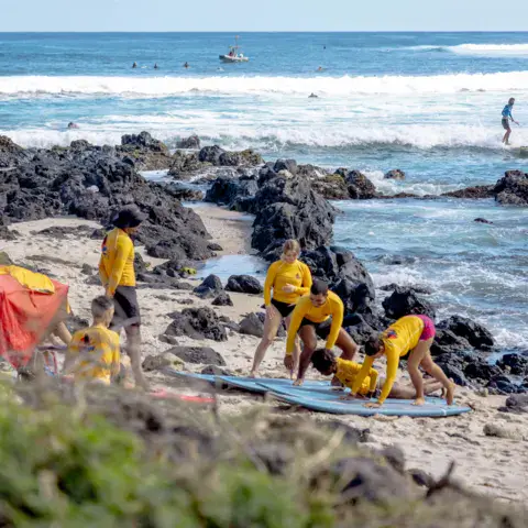 Élèves en rashguard jaune sur la plage avant le cours
