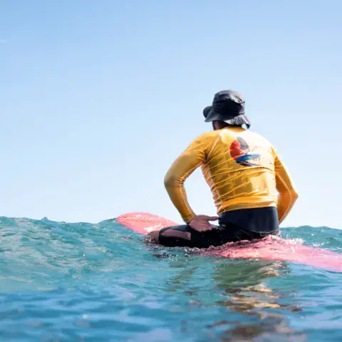 Moniteur assis sur sa planche dans l'eau