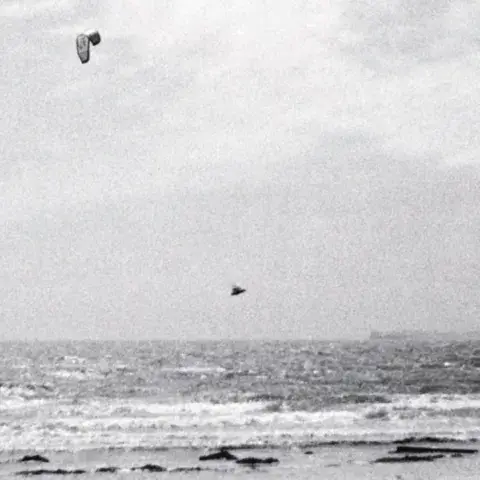 Aile de kite dans le ciel au-dessus de la mer (noir et blanc)