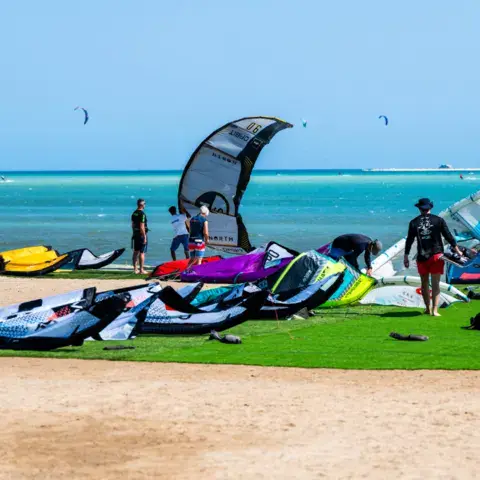 Matériel de kite étalé sur la pelouse devant la plage
