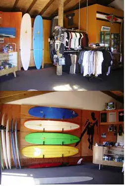 Intérieur de l'atelier-boutique, planches rangées au mur et vêtements en rayon