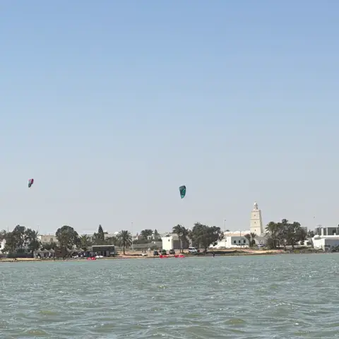 Kitesurfeurs sur la lagune, village en arrière-plan
