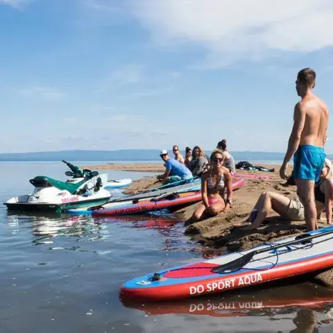 Groupe de paddle sur une plage de sable, jet-skis et planches au bord de l'eau