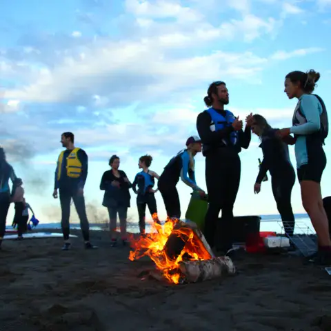 Soirée de groupe sur la plage autour d'un feu