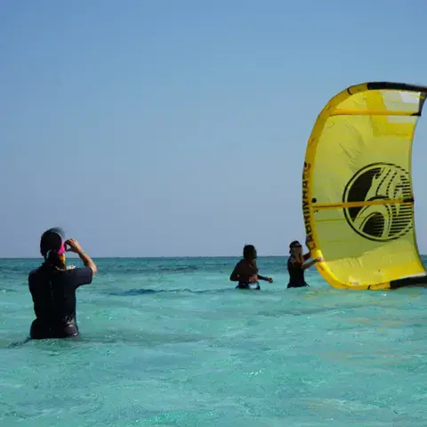 Moniteurs et élèves avec une aile de kite jaune dans l'eau