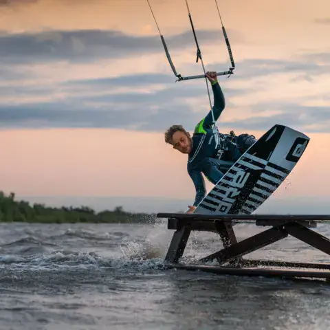Kitesurfeur sur un obstacle flottant au coucher du soleil
