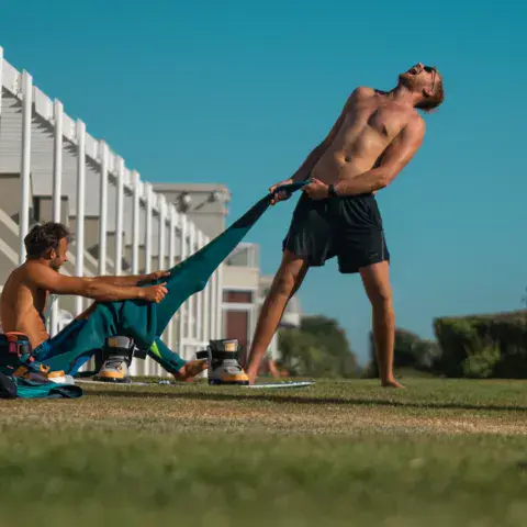 Deux kiteurs préparent une aile sur l'herbe
