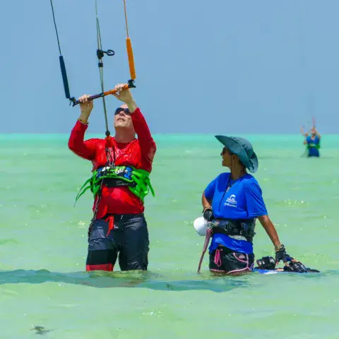Moniteur et élève debout dans le lagon pendant un cours de kitesurf