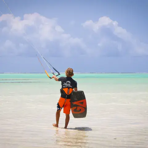 Kitesurfeur de dos dans l'eau peu profonde du lagon