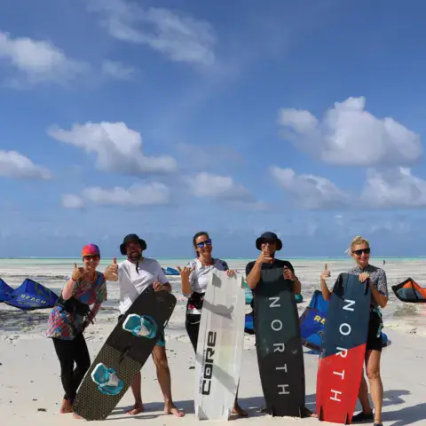 Groupe d'élèves avec leurs planches et leurs ailes sur la plage