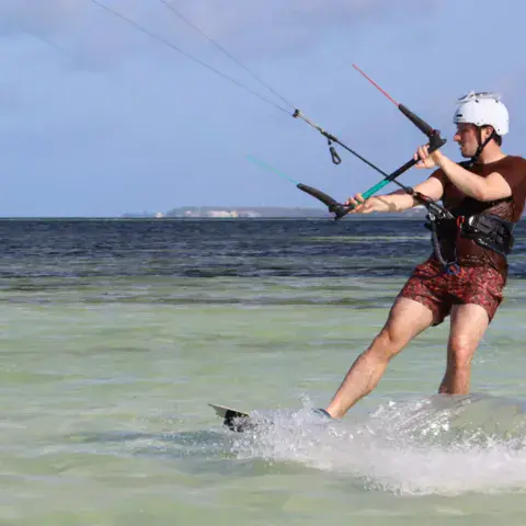 Kitesurfeur casqué qui navigue dans l'eau turquoise