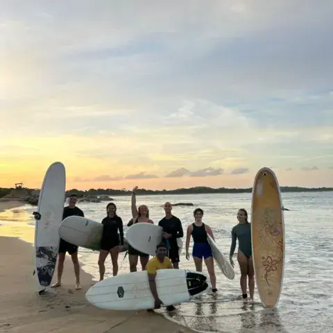Surfeurs avec leurs planches sur la plage au coucher du soleil