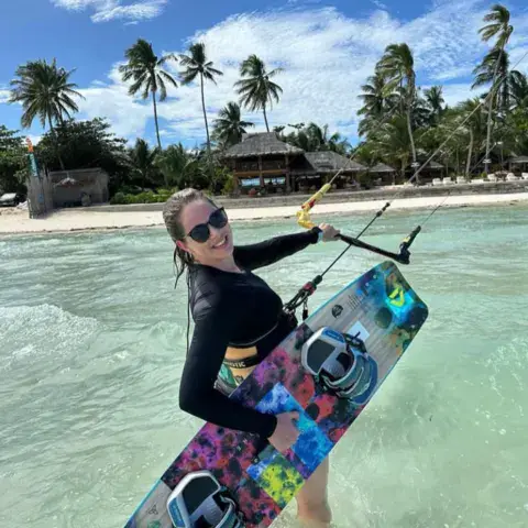 Élève dans l'eau peu profonde avec sa planche